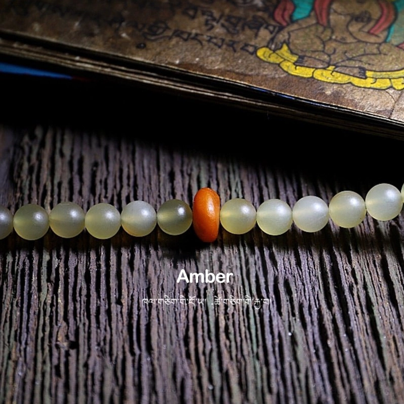 Tibetan sheep horn mala beads bracelet on wrist with dark green tassel and silver jewelry pairing