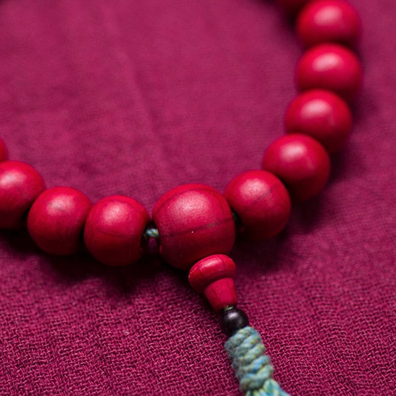 Clenched fist wearing red wooden tibetan mala bracelet overhead flat lay view