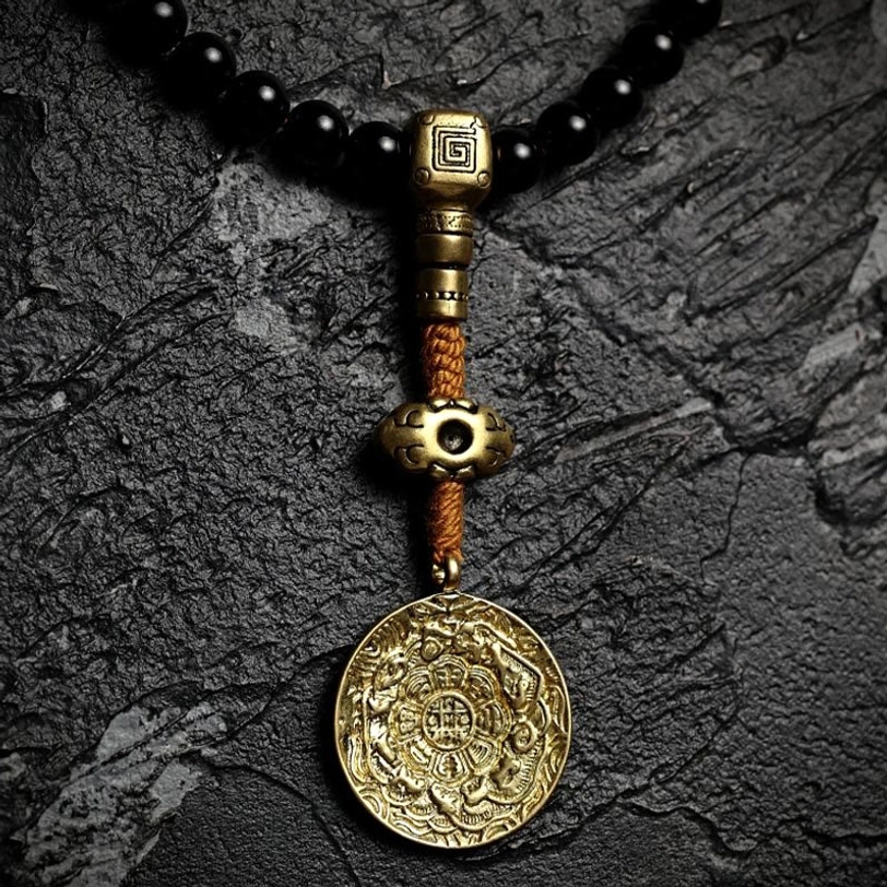 Tibetan 108-bead mala bracelet with nine palaces bagua protection amulet in brass and black onyx on light beige background