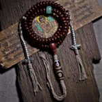 Tibetan 108 mala bracelet with purple bodhi seeds, copper dorje counters, and three-eyed dzi bead on Sanskrit wooden board