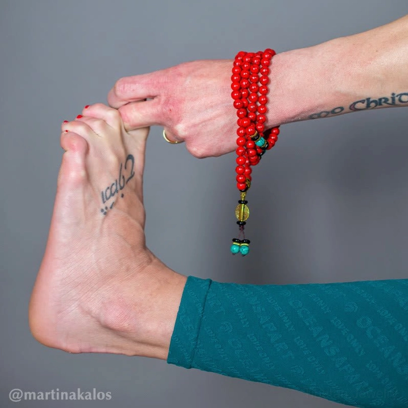 Tibetan prayer bead bracelet on tattooed wrist showing red turquoise and bronze hardware details