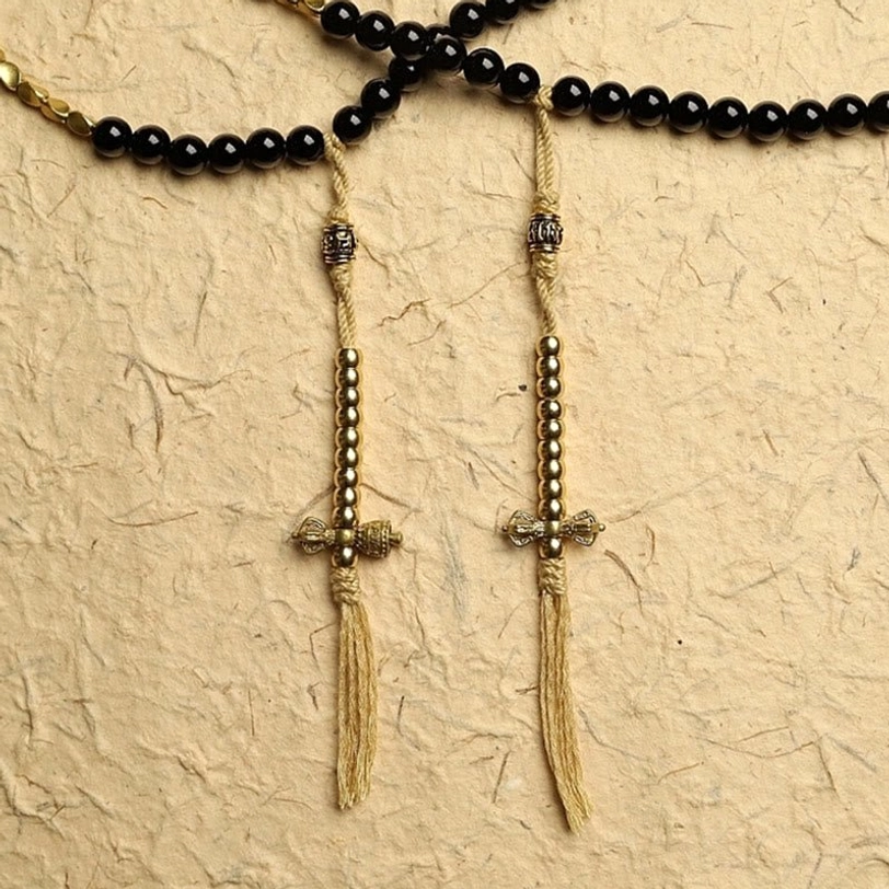 Handcrafted mala bracelet tassels with brass dorje charms and black beaded strands close-up