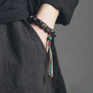 Ebony wood mala bracelet worn on wrist with dark linen clothing background