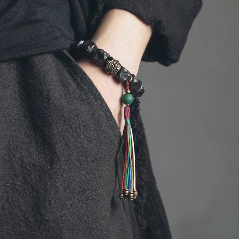 Ebony wood mala bracelet worn on wrist with dark linen clothing background