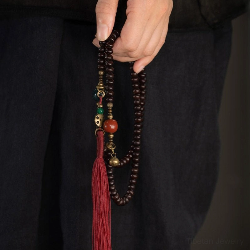 Purple bodhi seed mala bracelet worn on wrist showing full design with tassel and accents
