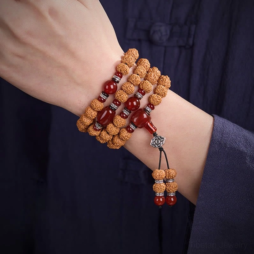 Bodhi seed mala worn as wrist bracelet with multiple wraps, showing brown seeds, red agate beads and silver metal spacers on wrist