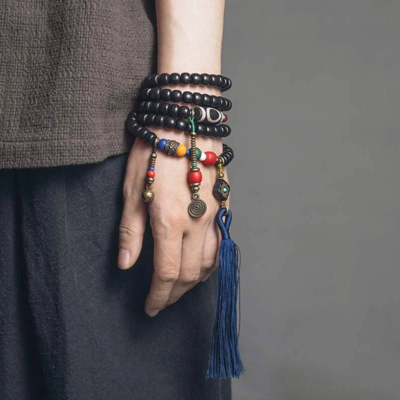 Tibetan 108-bead mala bracelet worn on wrist with casual outfit showing dzi bead and copper accents