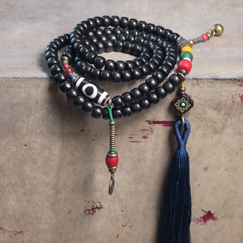 Coiled Tibetan 108-bead mala set with two tassels, dzi bead and mixed gemstone accents top-down view