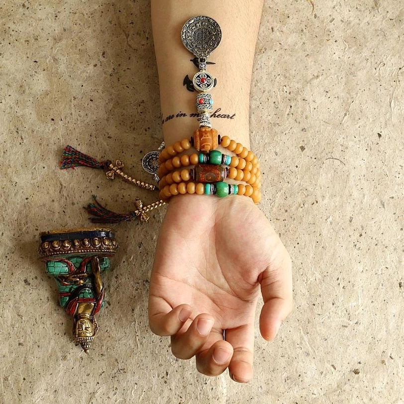 Detailed Tibetan 108 mala component breakdown showing labeled silver metal parts, tan main beads, copper Bagua pendant with stone inlays