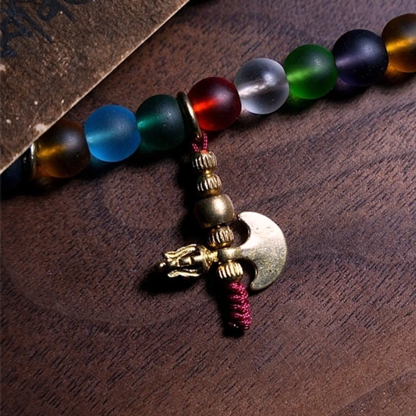 Partial mala bead strand with frosted multicolored glass beads and axe-shaped metal pendant, flat overhead close-up