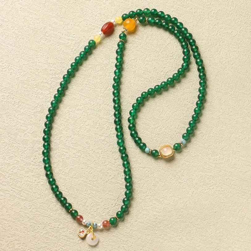 Extended Tibetan mala necklace with green agate beads and decorative end charms in side view