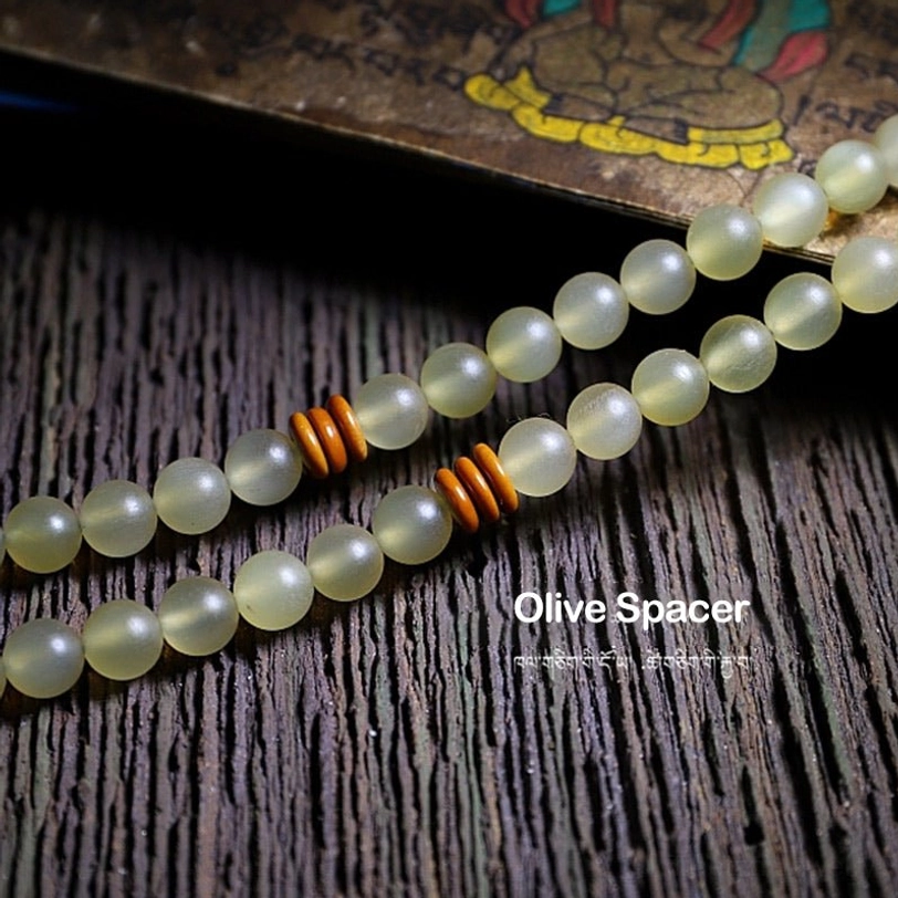 Tibetan 108 mala prayer beads bracelet with green tassel and dark diamond-shaped guru bead in palm