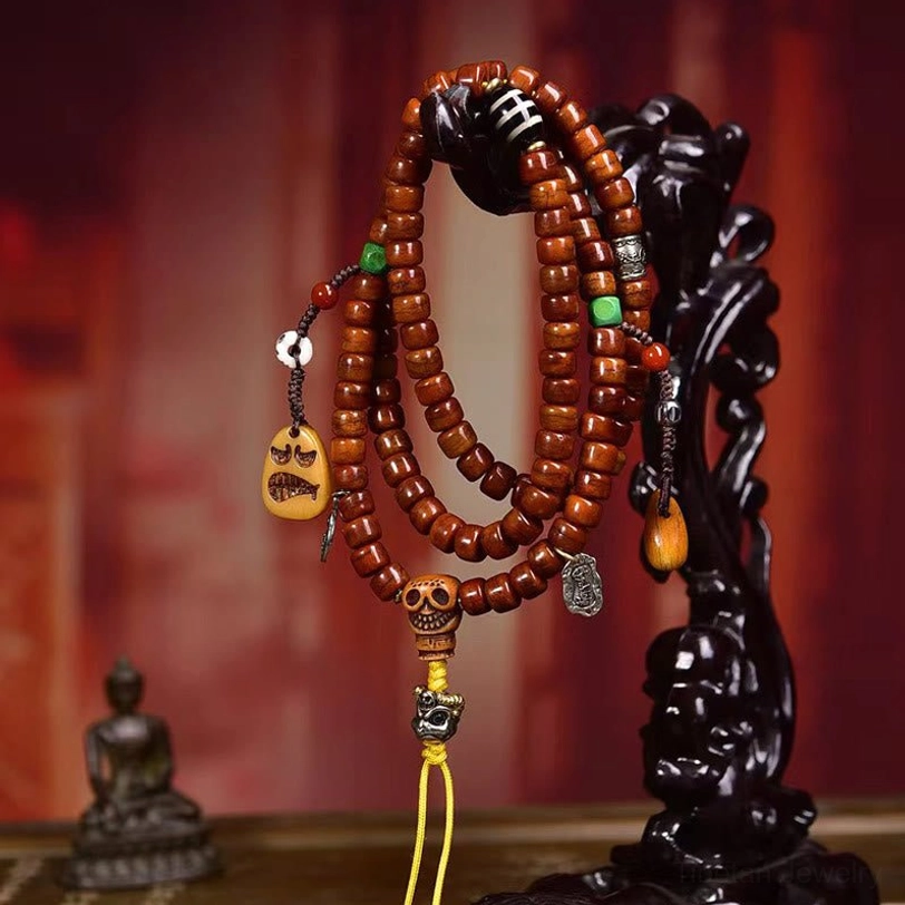 Tibetan bone bead mala necklace hanging on display stand with small Buddha figurine showing reddish-brown beads and silver metal accents