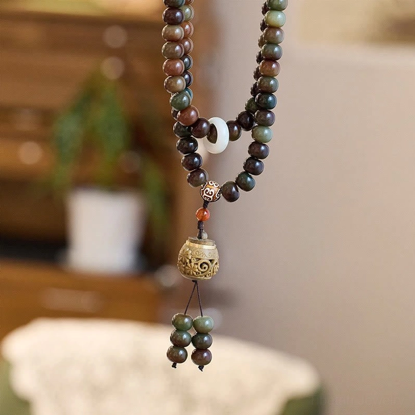 Hanging Tibetan mala bead necklace with white spacer bead and carved wooden meditation pendant display