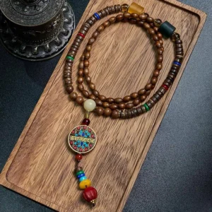 Tibetan handmade mala necklace with great bright mantra pendant and schima wood beads, flat lay on wooden tray