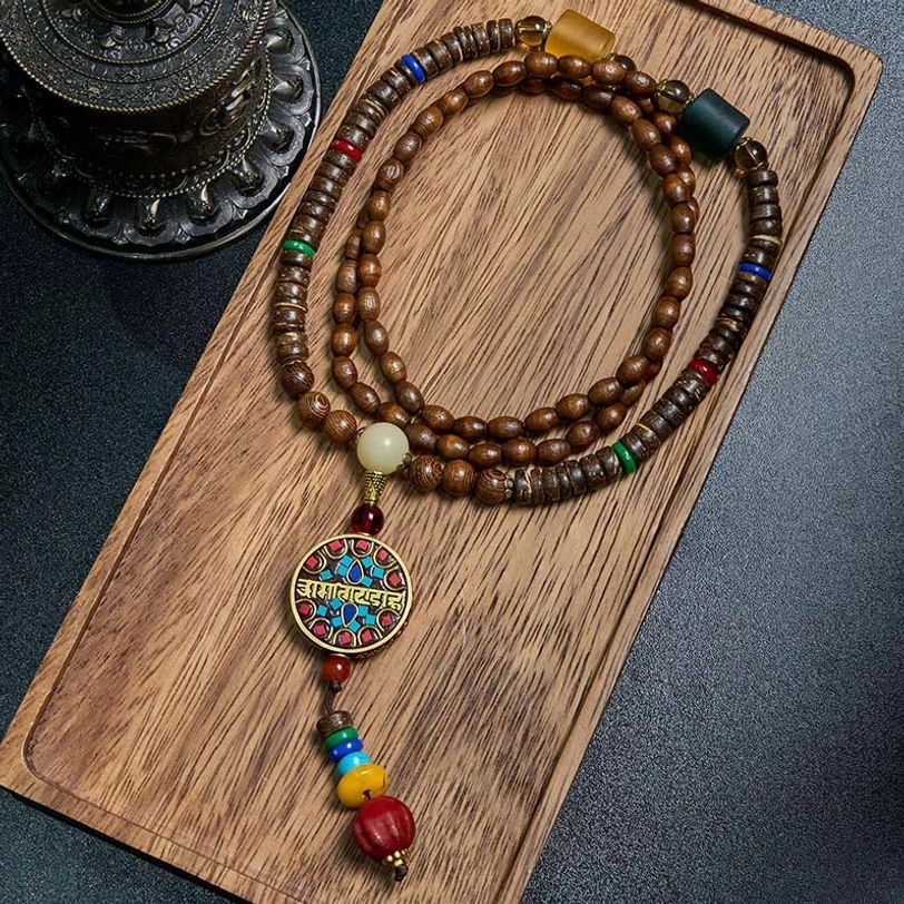 Tibetan handmade mala necklace with great bright mantra pendant and schima wood beads, flat lay on wooden tray