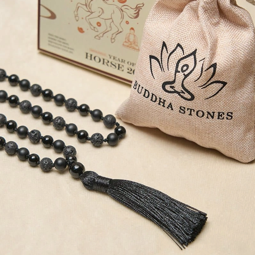 Loose tibetan mala necklace in flat lay with linen storage bag and branded packaging showing premium presentation