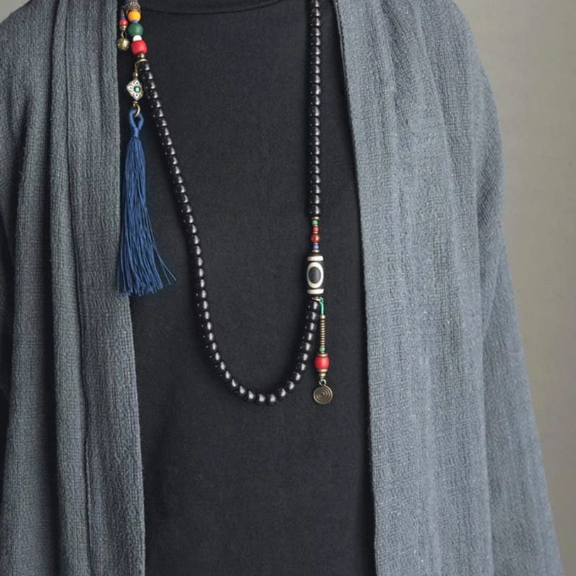 Tibetan 108-bead mala necklace side view with blue tassel and copper hardware on layered casual wear