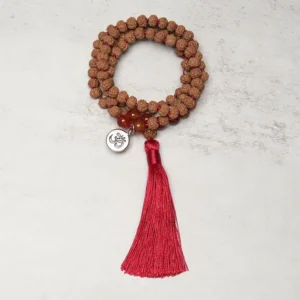 Tibetan prayer mala necklace Om charm close-up showing metal pendant and red silk tassel