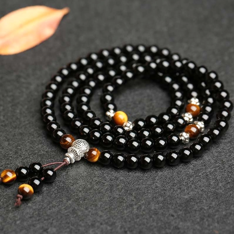 Circular wrap mala bracelet overhead view with multi-layer coiled beads, tiger eye and silver spacers, hanging bead tassel accent