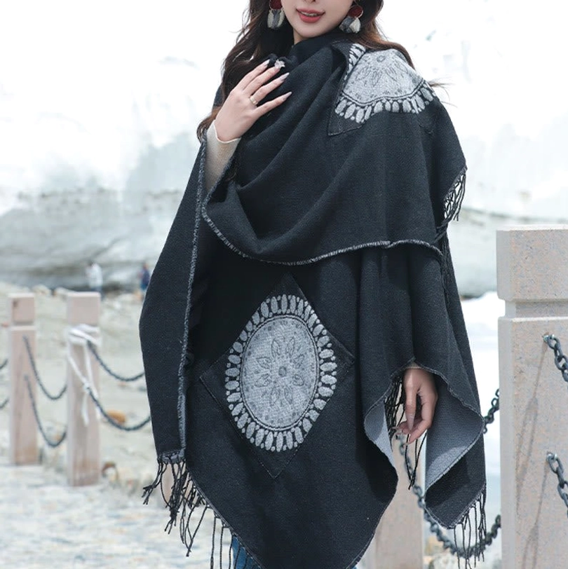 Black mandala poncho with grey embroidered patterns, close-up front view lakeside