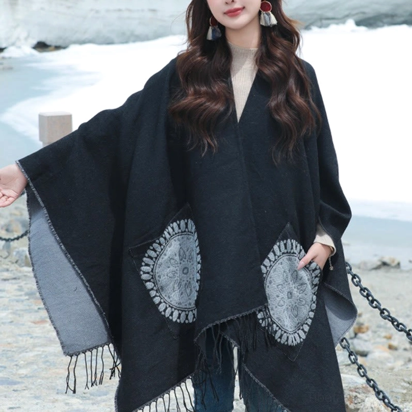 Black tassel mandala poncho with grey geometric designs, front side pose icy lakeside