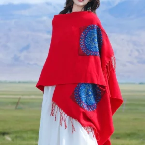 Red Tibetan mandala tassel shawl with blue geometric patterns, back view on mountain grassland