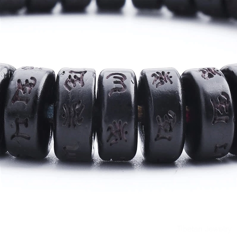Macro front view close-up of Tibetan mantra bracelet black disc beads with carved Om Mani Padme Hum Sanskrit and Tibetan script engravings