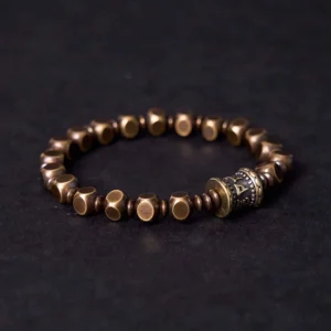 Tibetan mantra bracelet detail shot showing hand-carved brass bead with Om Mani Padme Hum inscription and faceted spacer beads