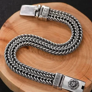 Side angle view of Tibetan Buddhist mantra bracelet showing double-woven braid structure and sacred metal clasp with emblem detail