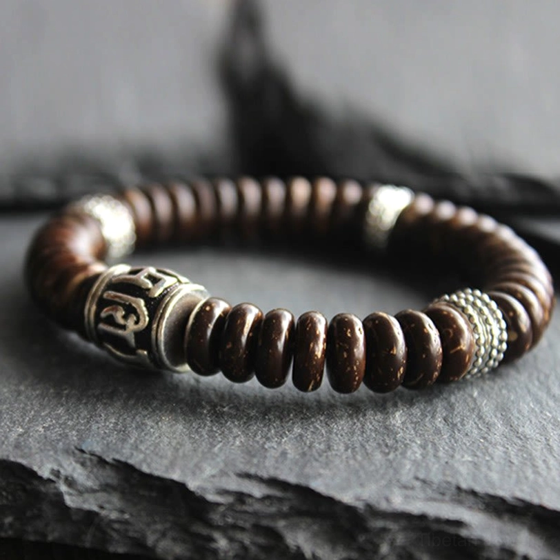 Angled view of Tibetan coconut shell bracelet showing textured silver metal decorative beads and wrapped construction