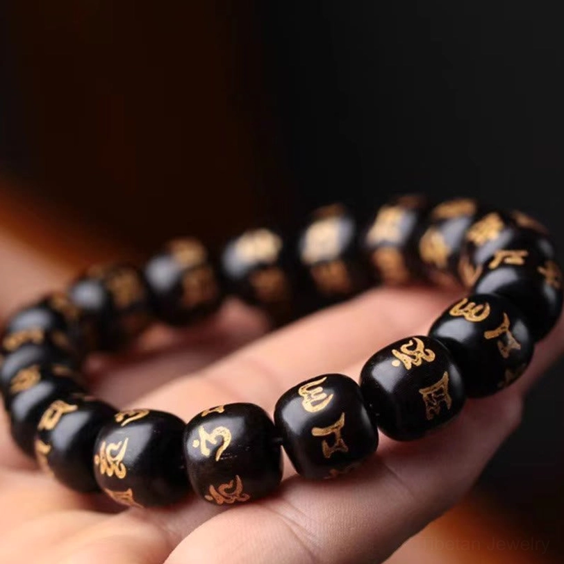 Tibetan spiritual bracelet worn on wrist showing Om Mani Padme Hum engraved beads with golden Sanskrit text in hand-held view