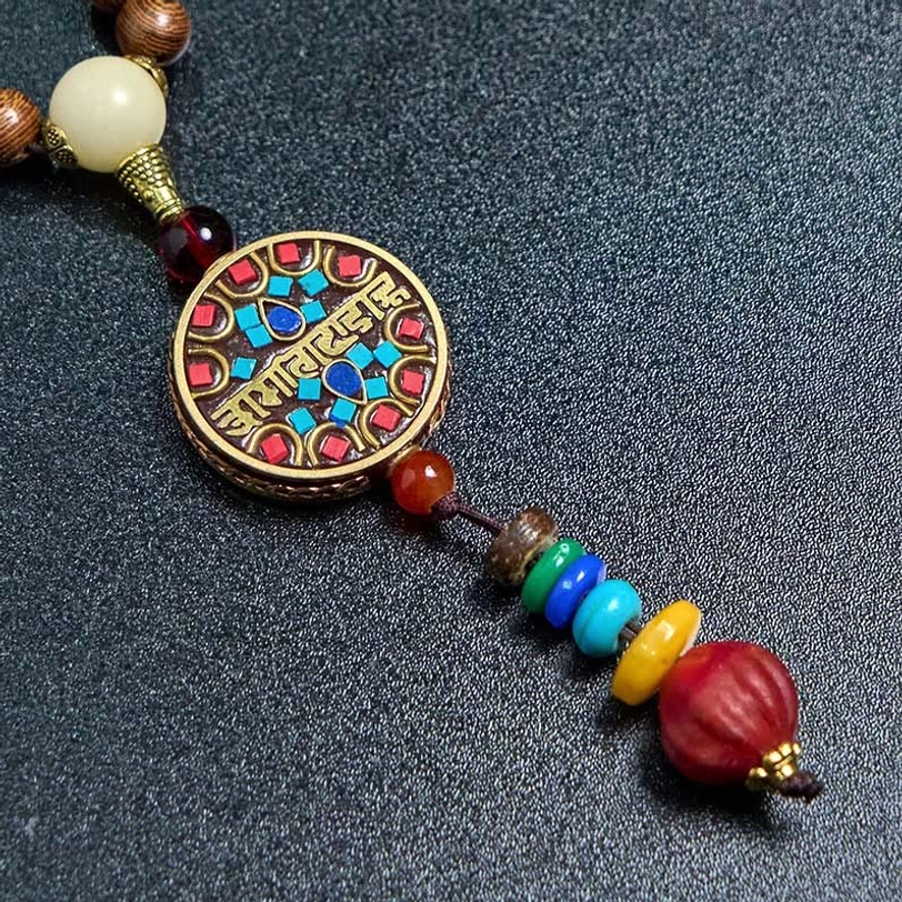 Close-up of Tibetan mantra pendant with creamy white coconut shell bead and multicolor accent beads
