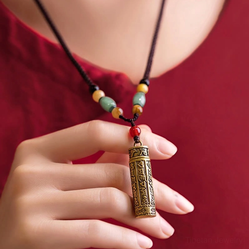 Sacred Tibetan Buddhist necklace pendant worn on neck, featuring engraved mantra and protective gemstone beads in close-up detail