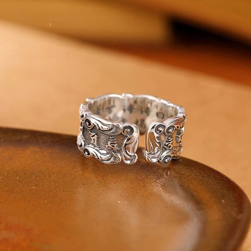 Tibetan Buddhist mantra adjustable ring, polished vintage silver with ornate carved edges and inner engraved text, low oblique angle