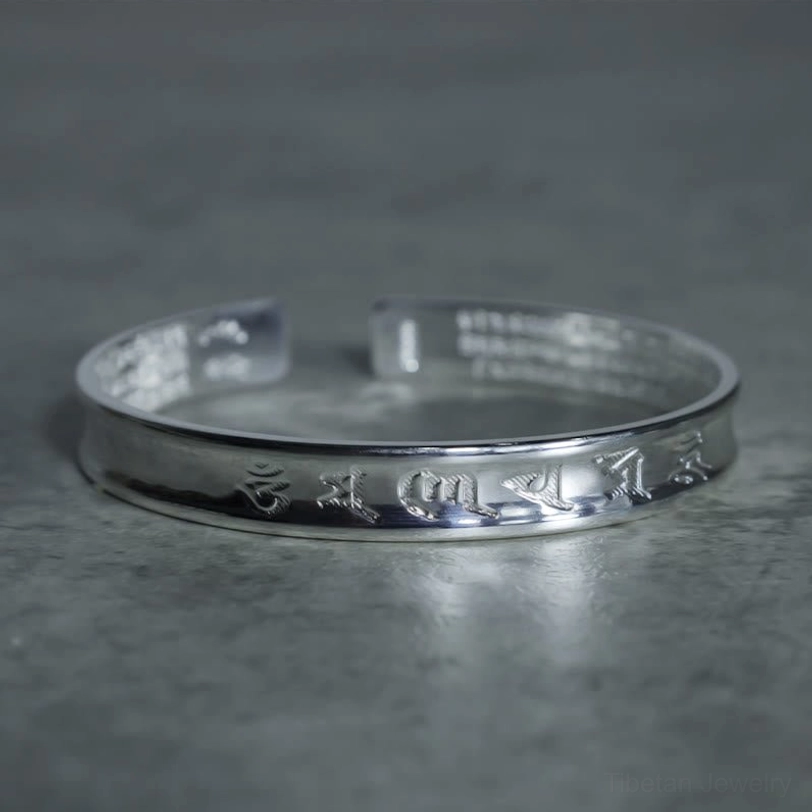 Tibetan mantra silver cuff bracelet frontal overhead view with clear engraved Om Mani Padme Hum text on outer band