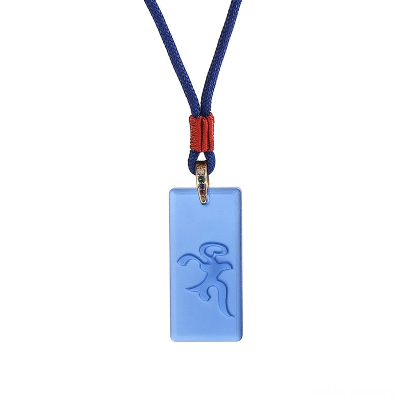 Flat lay view of Medicine Buddha Tibetan healing necklace with dark blue braided cord and red decorative knot, rectangular crystal glass pendant