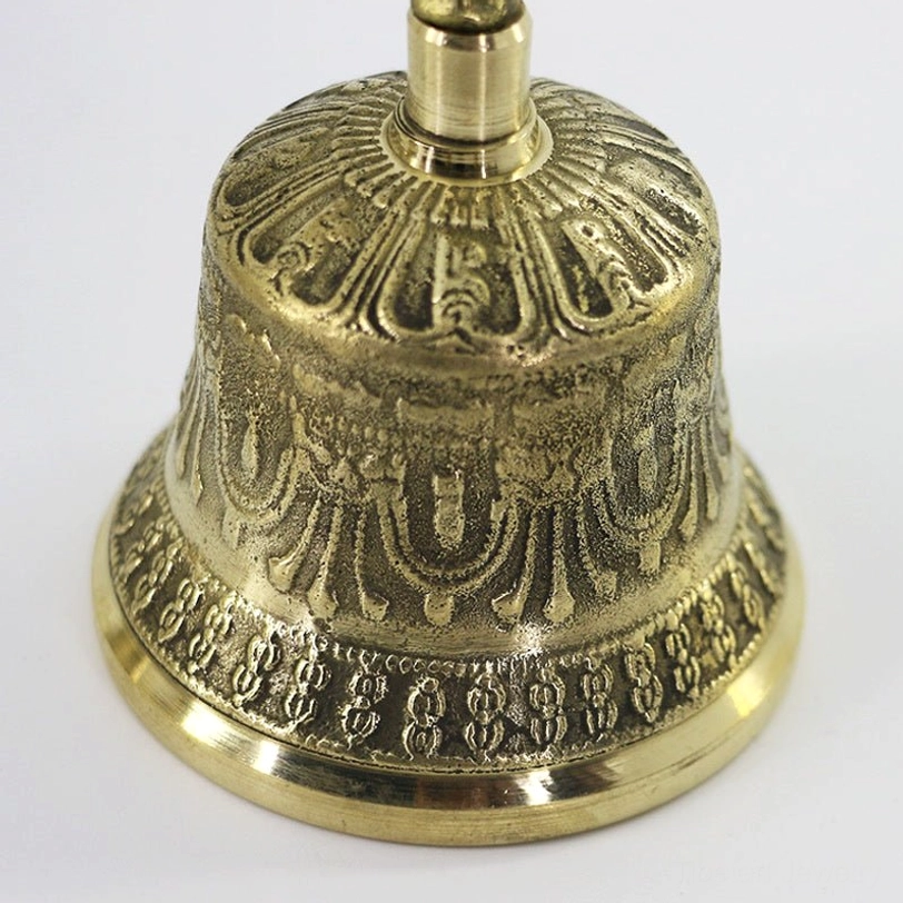 Close-up detail of Tibetan meditation bell showing intricate carved brass patterns and polished surface finish