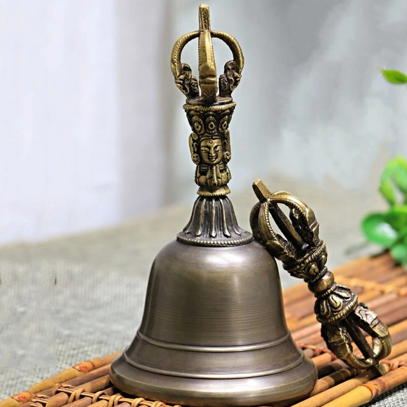 Tibetan copper bell and dorje ritual instrument set shown from side angle, featuring intricate carved handle details and vintage bronze finish