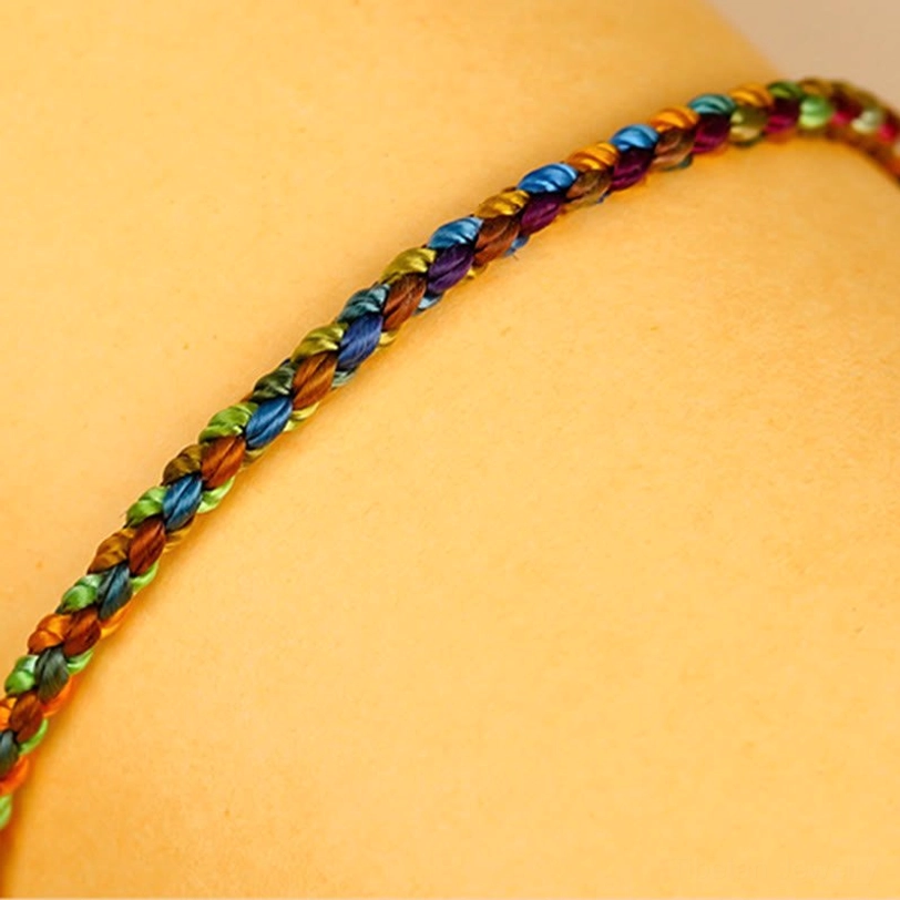 Slim braided Tibetan protection bracelet macro side view showing tight braided texture and glossy rainbow colors