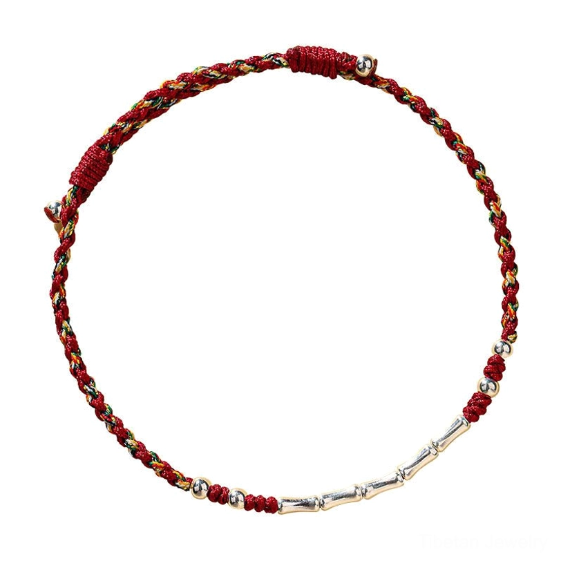 Full view handmade Tibetan braided protection bracelet with red, yellow, and green multicolor threads and silver bamboo-shaped beads