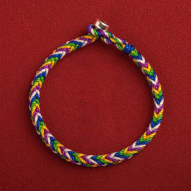 Five-color braided Tibetan protection bracelet with alloy clasp, flat lay top-down view on red background