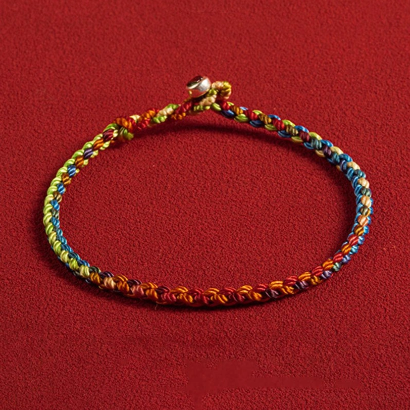 Handwoven Tibetan multicolored protection bracelet with silver clasp, front view on red background