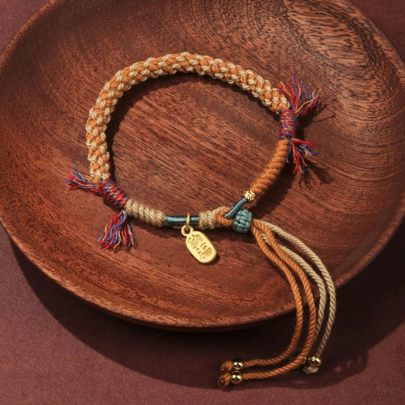 Tibetan hand-woven Nafu luck bracelet with colorful rope and Fu charm, top-down view on wooden plate