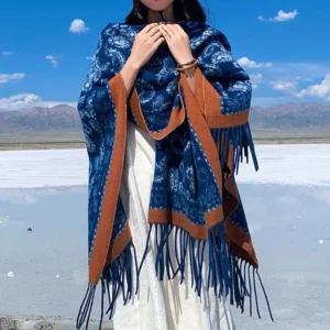 Handwoven Tibetan paisley shawl with brown trim and long tassels, front view worn with white dress at scenic mountain location