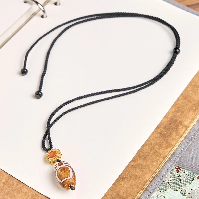 Adjustable black braided cord dzi bead necklace flat lay showing sliding knot closure mechanism