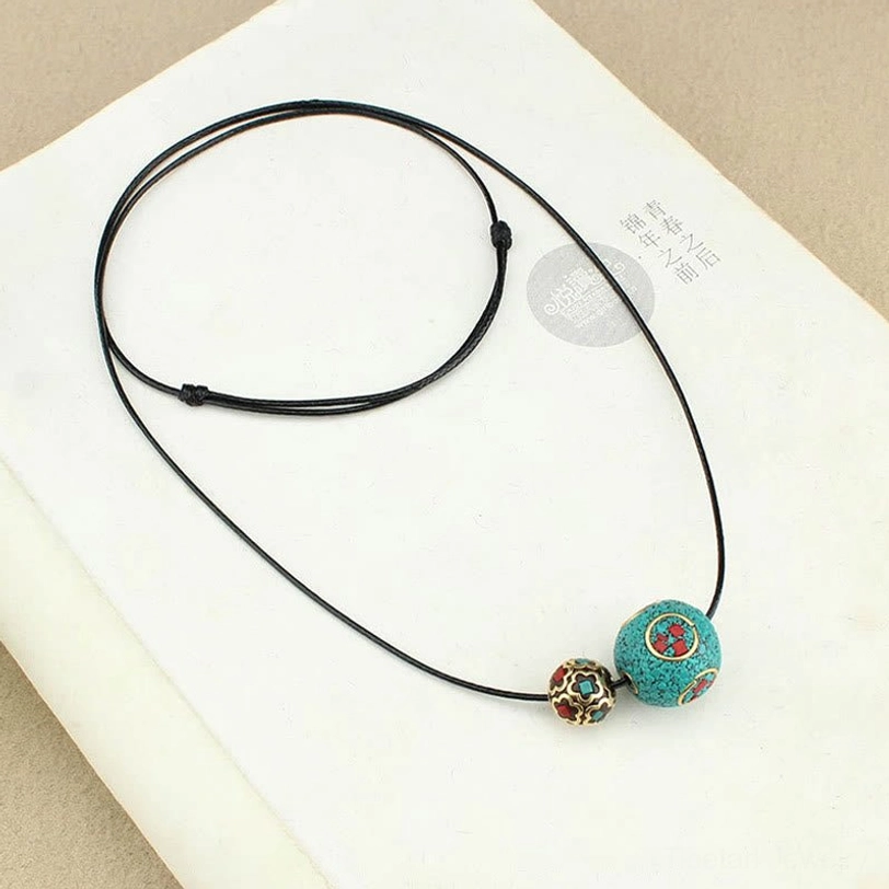 Adjustable Tibetan turquoise necklace laid on open book showing full length with adjustable knots and wax cord