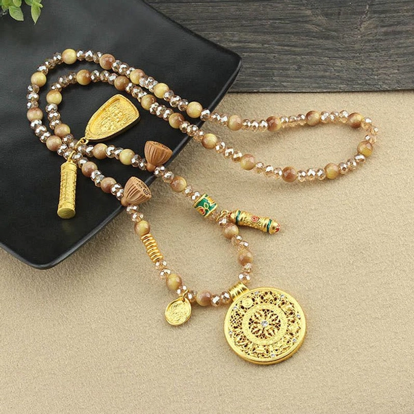 Tibetan lotus necklace displayed on black tray with golden round pendant and decorative beads