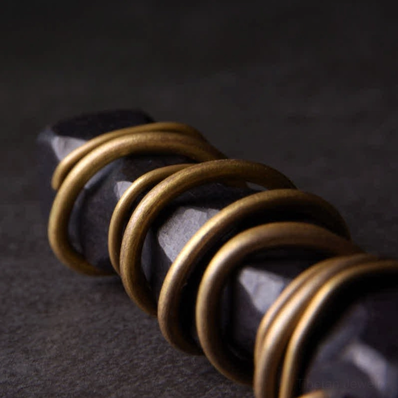 Detailed macro photograph of tightly wound brass wire on matte black ebony wood, highlighting artisanal metalwork technique