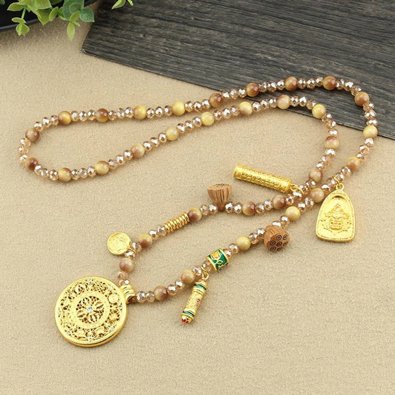 Tibetan beaded necklace laid out flat showing golden round lotus pendant and tiger eye beads
